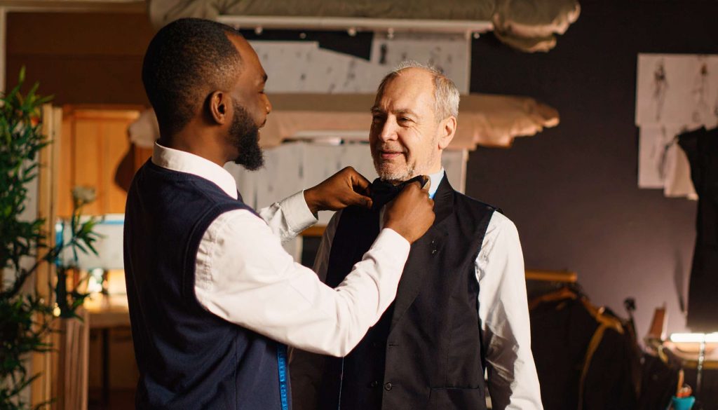 A client trying on a final suit laughing with the tailor